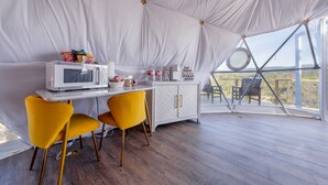 A tent with a dining area, a microwave, and a cabinet.
