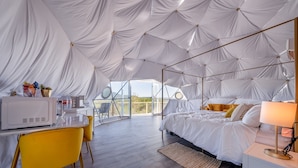 A tented room with a bed, a desk, and a chair.