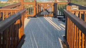 Eine Holzterrasse mit einem Metallrostboden, der zum Blick auf den Strand führt.