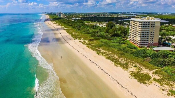 Ein Küstenhotel mit Blick auf den Strand, ein großes Gebäude und ein klarer Himmel.