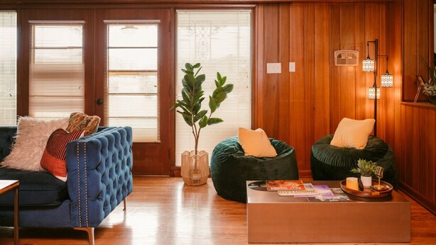 A cozy living room with a blue sofa, green bean bag, and a coffee table with magazines.