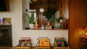 A cozy room with a brick wall, wooden paneling, a vintage television, and a shelf with Pepsi crates and music memorabilia.