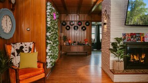 A cozy living room with a wooden floor, a fireplace, and a wall adorned with vinyl records.