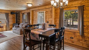 A wooden cabin interior with a dining table, chairs, a sofa, and a fireplace. - The Bucking Moose (West Yellowstone)