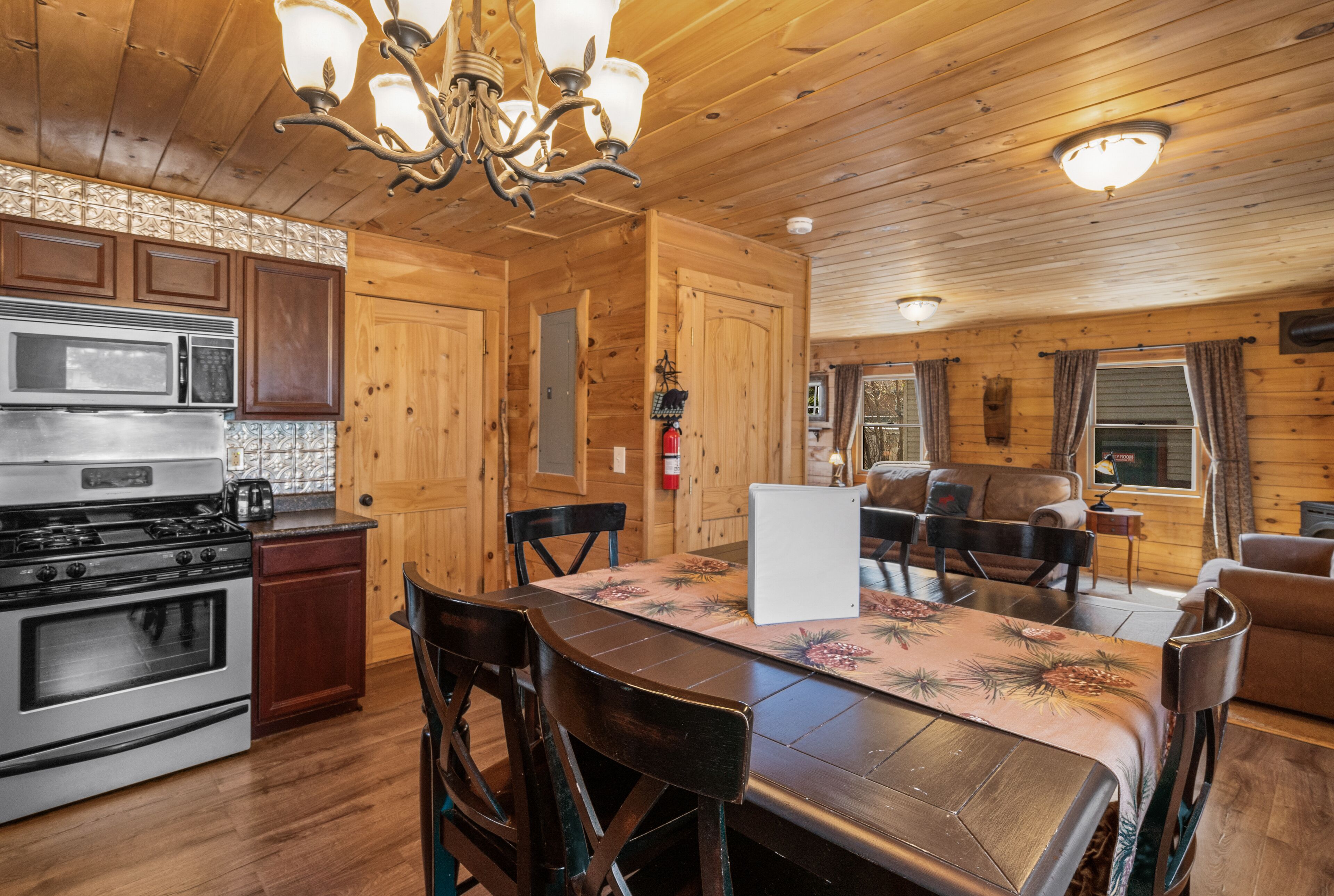 A wooden cabin interior with a kitchen, dining area, and living room.