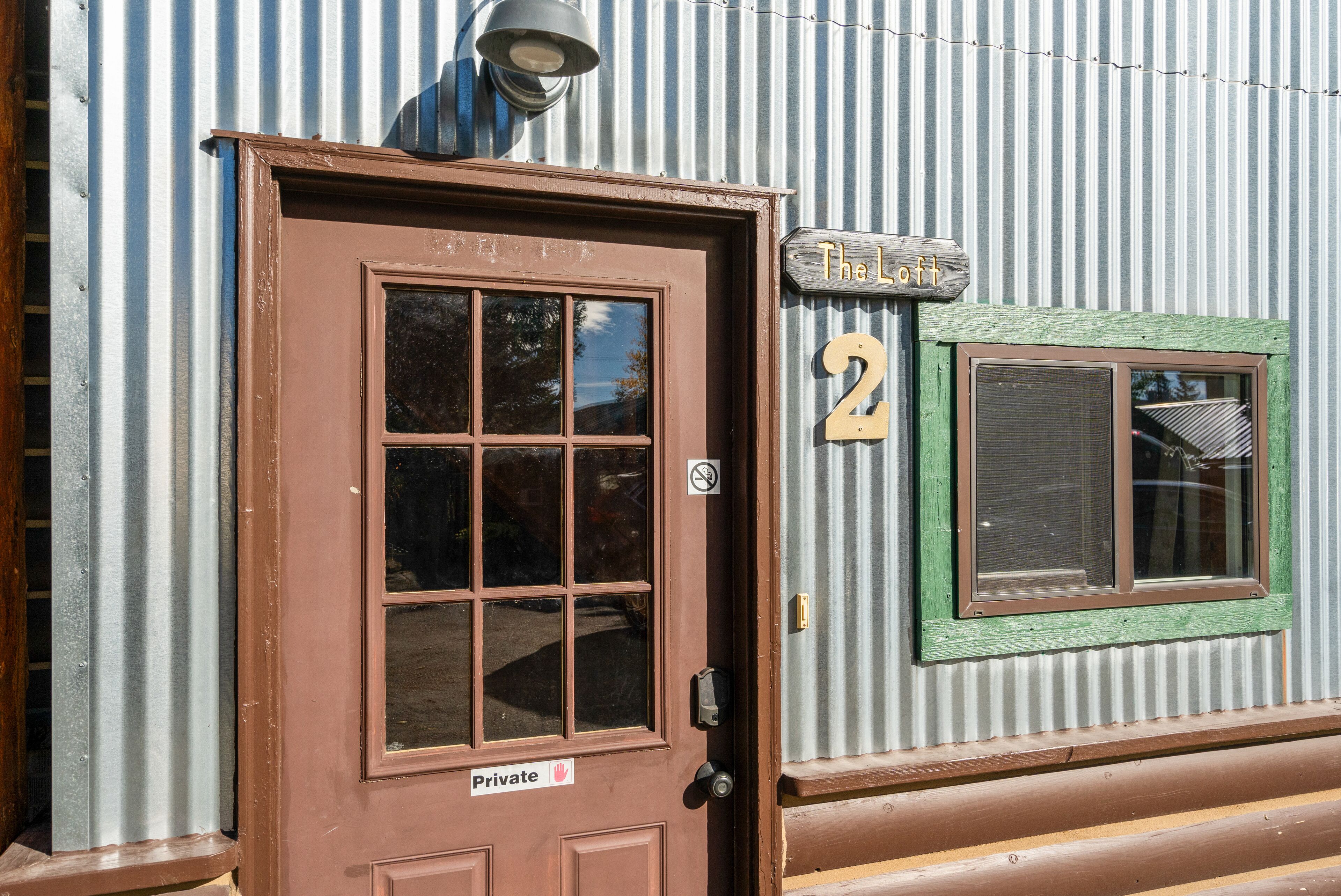 Un bâtiment en métal ondulé avec une porte marron portant l’inscription « Privé » et une enseigne au-dessus indiquant « The Loft 2 ».