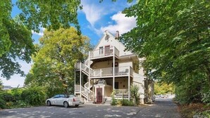 A two-story house with a balcony, a driveway, and a car parked in front.