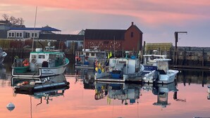 A marina with boats docked, a red building, and a calm water surface reflecting the surroundings.