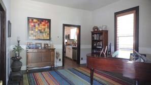 Relax in this stylish living area with a grand piano, colorful rug, and artwork.