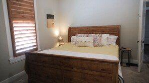 Cozy retreat with a comfortable bed, bedside table, and window with blinds.