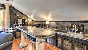 A modern kitchen with a marble countertop, a sink, and a bar area with stools. - Greenville Apt w/ Patio: Work, Play & Unwind! (Greenville)