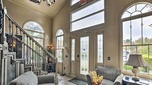 A spacious living area with a staircase, large windows, and a cozy seating arrangement. - Greenville Apt w/ Patio: Work, Play & Unwind! (Greenville)