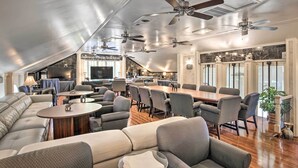 A spacious living area with a high ceiling, multiple ceiling fans, a large dining table, and comfortable seating. - Greenville Apt w/ Patio: Work, Play & Unwind! (Greenville)