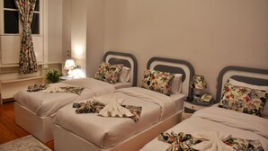 A hotel room with two beds, floral-patterned bedding, a bedside lamp, a nightstand with a phone, and a window with curtains. - columbia sky city (Cairo)