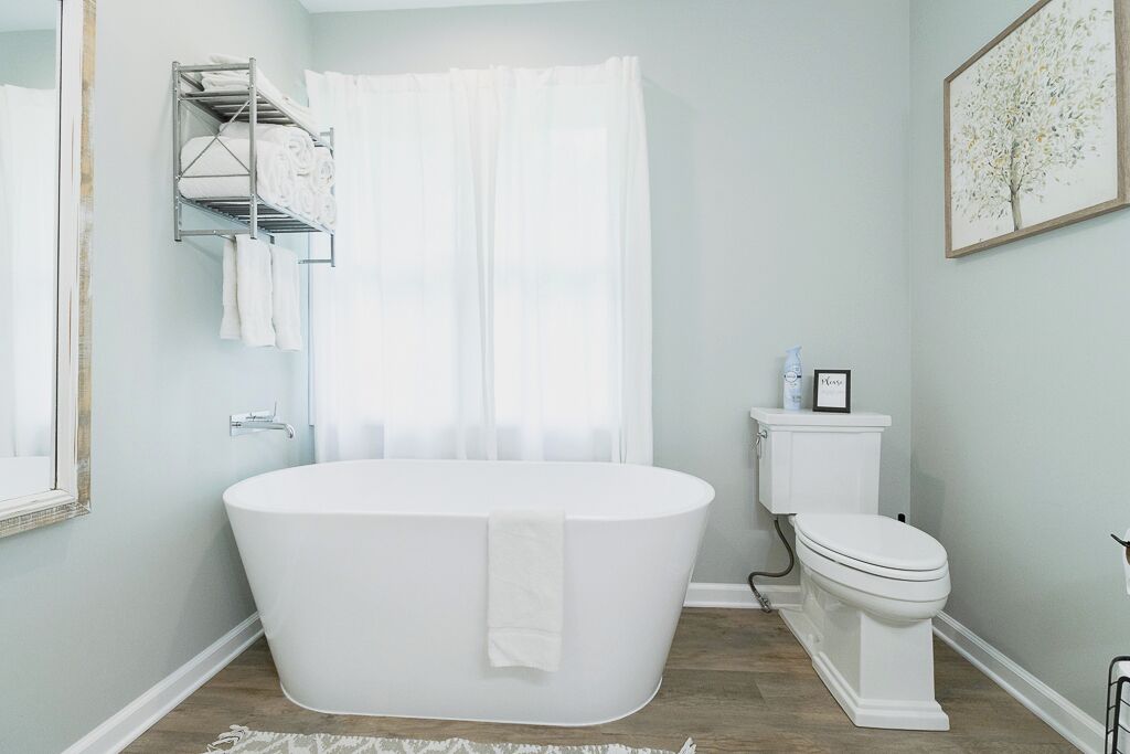 Un baño moderno con una bañera independiente, un inodoro y una cortina de ducha.