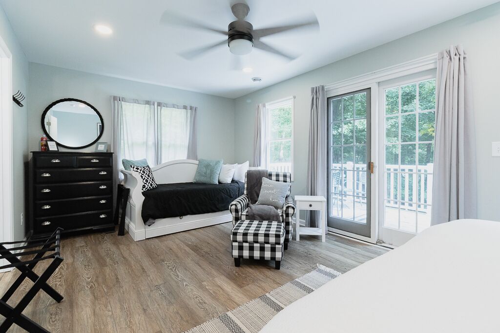 Un dormitorio con cama, cómoda, silla y ventana.