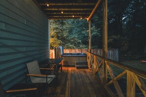 Una terraza de madera con un jacuzzi, sillas y baranda de madera.