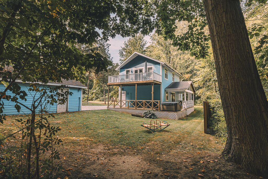 A two-story house with a balcony, a fenced yard, and a swing set.