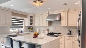 Una cocina moderna con una isla grande, electrodomésticos de acero inoxidable y encimeras de mármol.