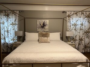 A four-poster bed with a floral-patterned canopy, a central floral artwork, and two bedside lamps. - Anita’s Home, private pool and hot tub. (Roswell)