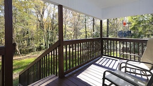 A wooden deck with a chair, surrounded by trees and a clear view of the outdoors. - Charming Country Cottage Retreat -  Walking distance to Downtown (Dallas)