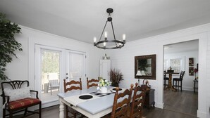 A dining room with a white table and wooden chairs, a chandelier, and a door leading to another room. - Charming Country Cottage Retreat -  Walking distance to Downtown (Dallas)