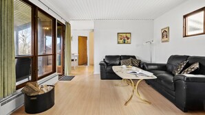 Un salon moderne avec un canapé en cuir noir, une table basse en marbre et un plancher en bois.