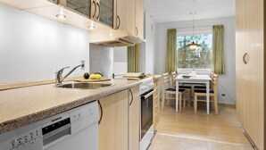 Une cuisine moderne équipée d’un lave-vaisselle, d’une cuisinière et d’un coin repas avec des chaises et une table.