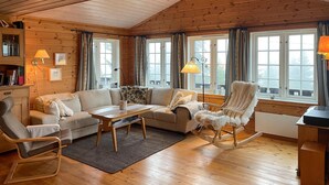 A cozy cabin interior with a wooden ceiling, a sofa, a rocking chair, and a table. - Stunning home in Sjusjøen with sauna (Sjusjøen)