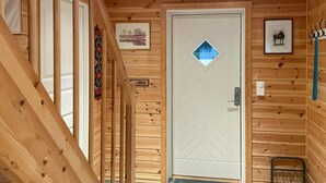 A wooden interior with a white door featuring a diamond-shaped window, a small sign above the door, and a coat rack with hooks. - Stunning home in Sjusjøen with sauna (Sjusjøen)