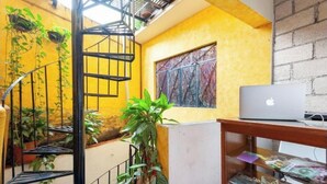 A room with a spiral staircase, a laptop on a desk, and a window with a decorative screen.