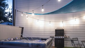 An outdoor patio with a hot tub, grill, and string lights. - 🏝️LUX Hot Tub +Chiller Near DT: Spa Baths, Yard Games, Arcade, Parking, SLEEPS 18 (Austin)