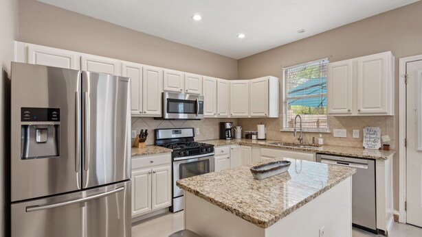 A modern kitchen with stainless steel appliances, white cabinetry, and a granite countertop island. - 🏝️LUX Hot Tub +Chiller Near DT: Spa Baths, Yard Games, Arcade, Parking, SLEEPS 18 (Austin)