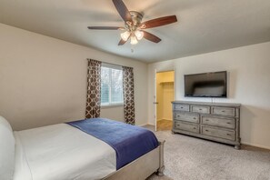 A bedroom with a bed, a ceiling fan, a dresser, and a TV. - Tranquility: Spacious Townhome Near It All (Grand Junction)