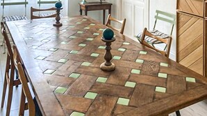 Een lange houten eettafel met een geometrisch patroon en twee decoratieve sferen op voetstukken.