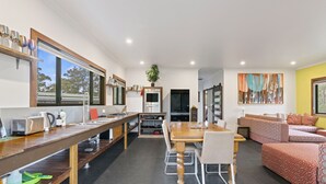 A modern kitchen with a dining area, a sofa set, and a large window with a view.