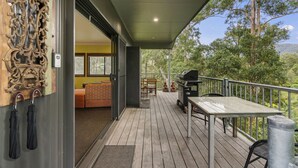 An outdoor deck with a grill, seating area, and a wooden wall with a decorative carving.