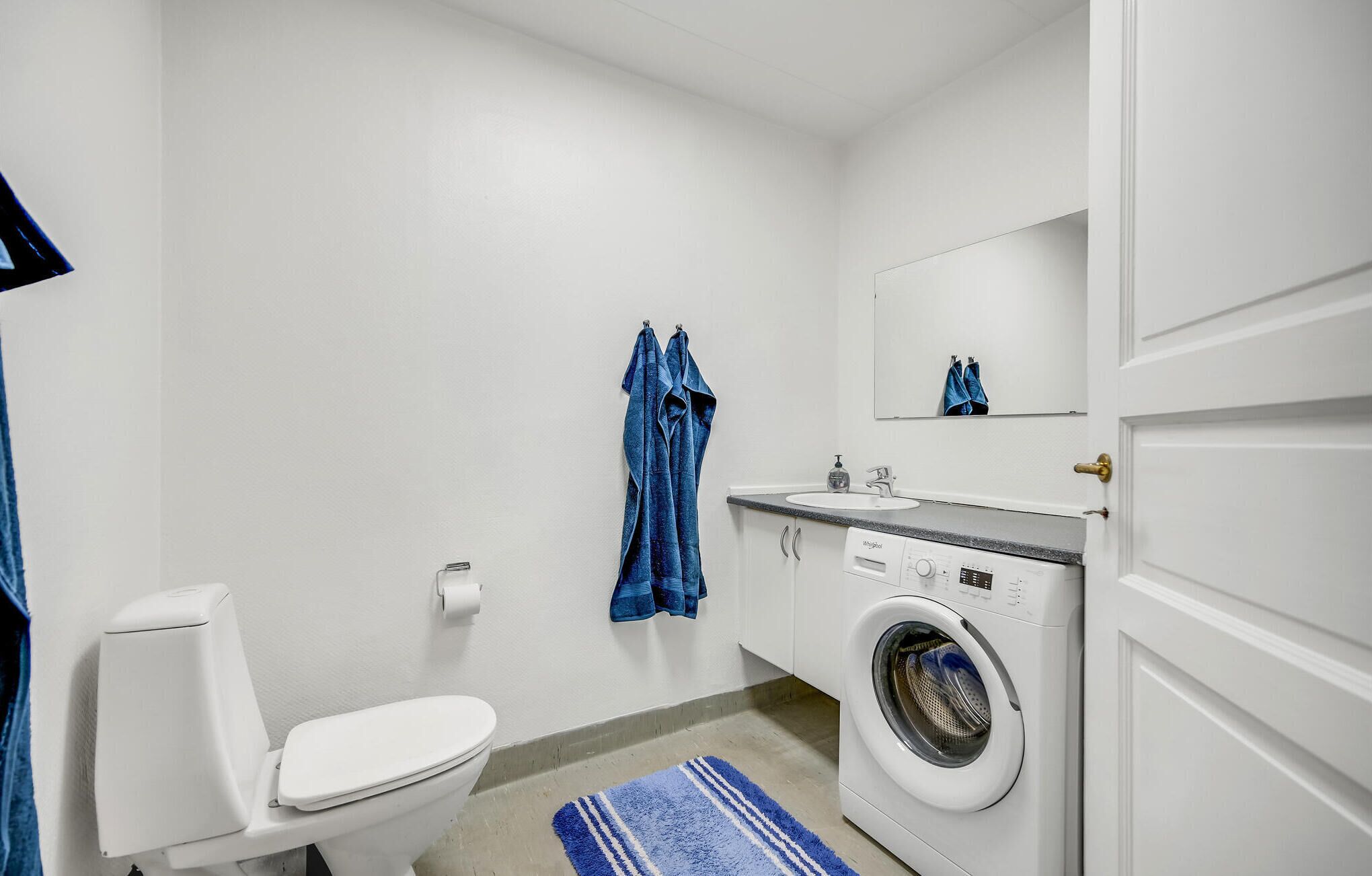 A compact bathroom with a toilet, washing machine, and sink.