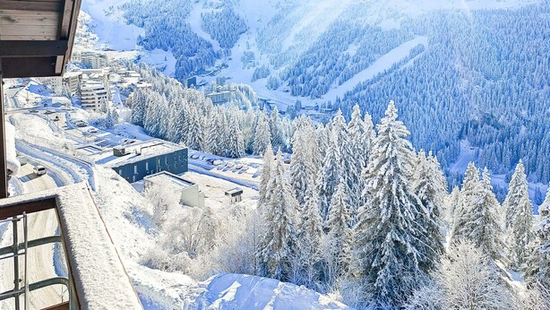 Un paysage de montagne enneigé, avec des bâtiments et des arbres.