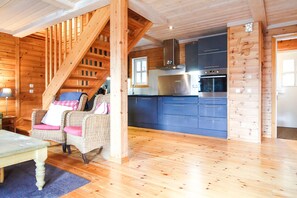 A wooden interior with a staircase, wicker furniture, and a kitchen area. - Large 3-bedroom beautiful alpine chalet (Flaine)