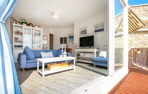 Un salon comprenant un canapé, une table basse, un téléviseur et un balcon avec un mur en pierre.
