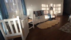 Un salon avec un canapé blanc, un fauteuil blanc, une petite table ronde et un tapis moelleux.