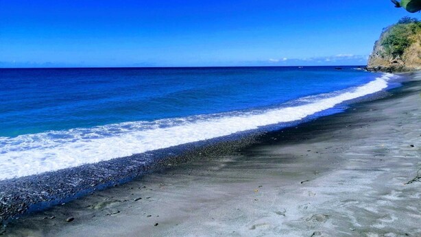 Ein Strand mit klarem, blauem Wasser und einer felsigen Küste.