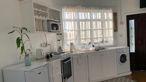 Eine kompakte Küche mit Mikrowelle, Backofen und Waschmaschine.