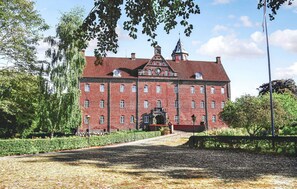 Stunning historic building with a central entrance and clock tower, surrounded by a beautifully maintained garden.