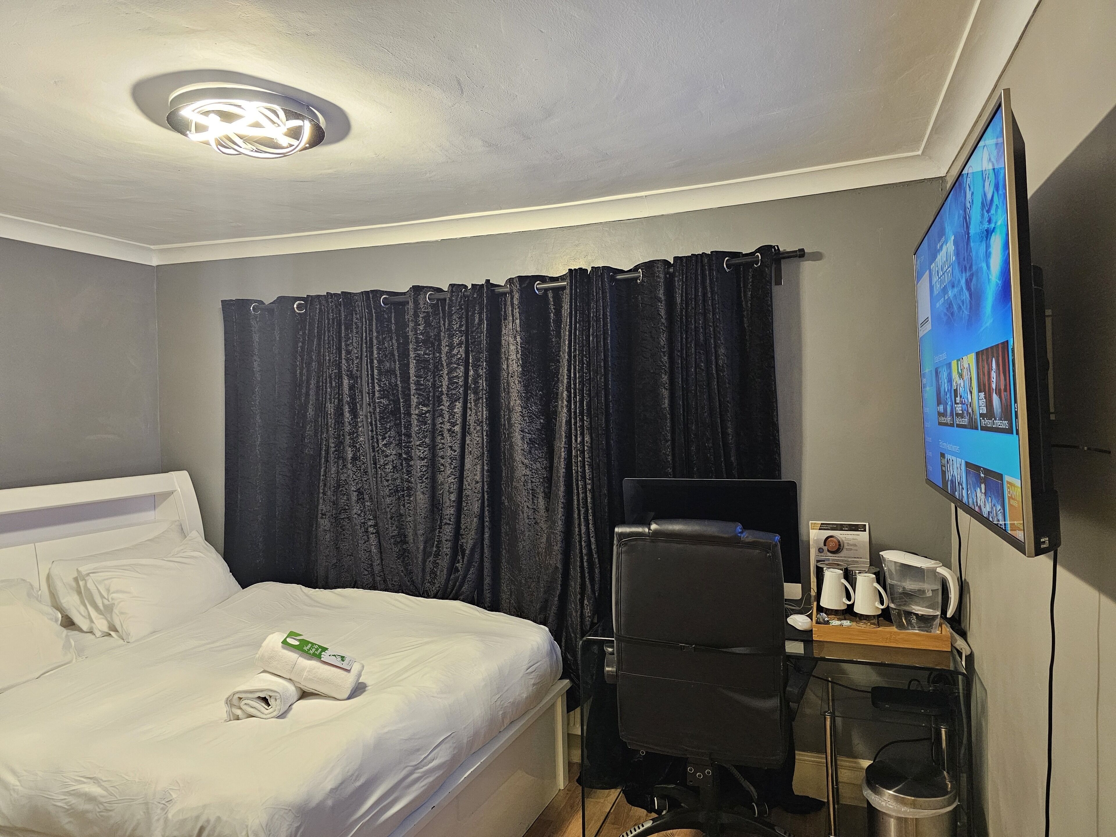 A hotel room with a bed, a desk with a chair, a TV, and a coffee maker.
