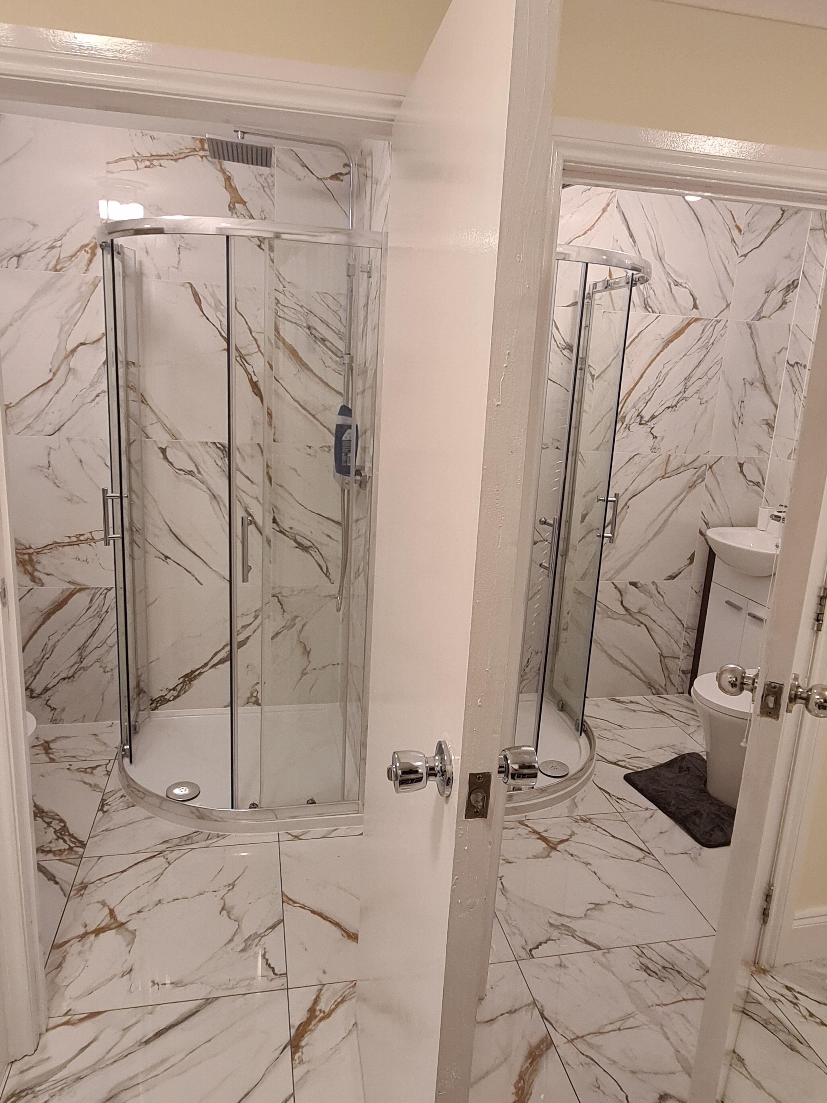 A bathroom with a glass-enclosed shower, a toilet, and a sink.