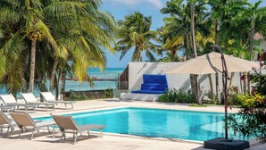 A pool area with lounge chairs, a blue water slide, and palm trees.