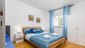 A bedroom with a wooden bed, a nightstand, a wardrobe, and a window with curtains.
