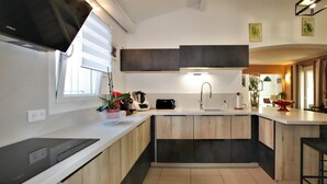 Une cuisine moderne avec un plan de travail blanc, des meubles noirs, un évier et une fenêtre.
